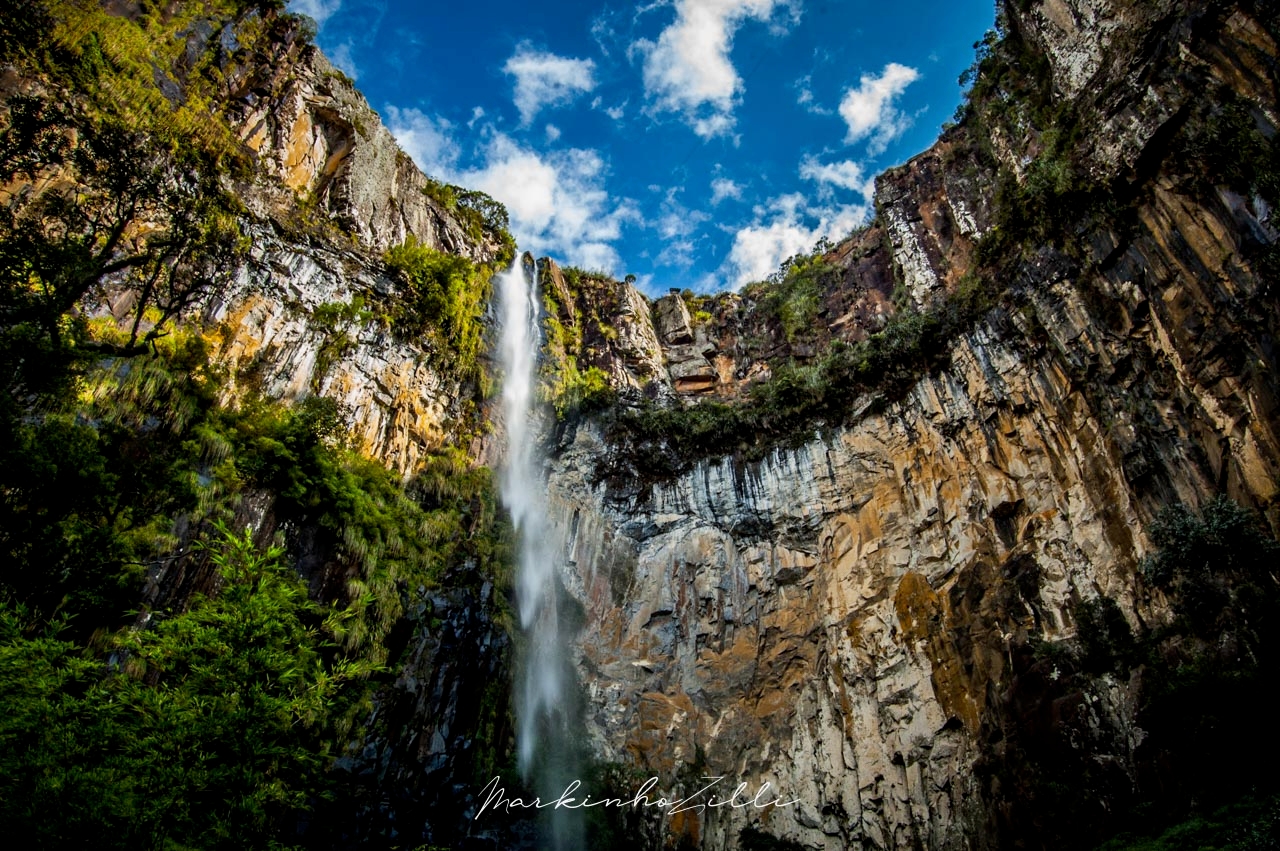 Cachoeira do Avencal em Urubici vista por baixo com paredão rochoso e sol cortando a queda d'água
