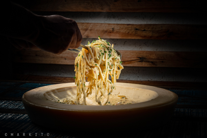 Espaguete à carbonara finalizado na peça de grana padano