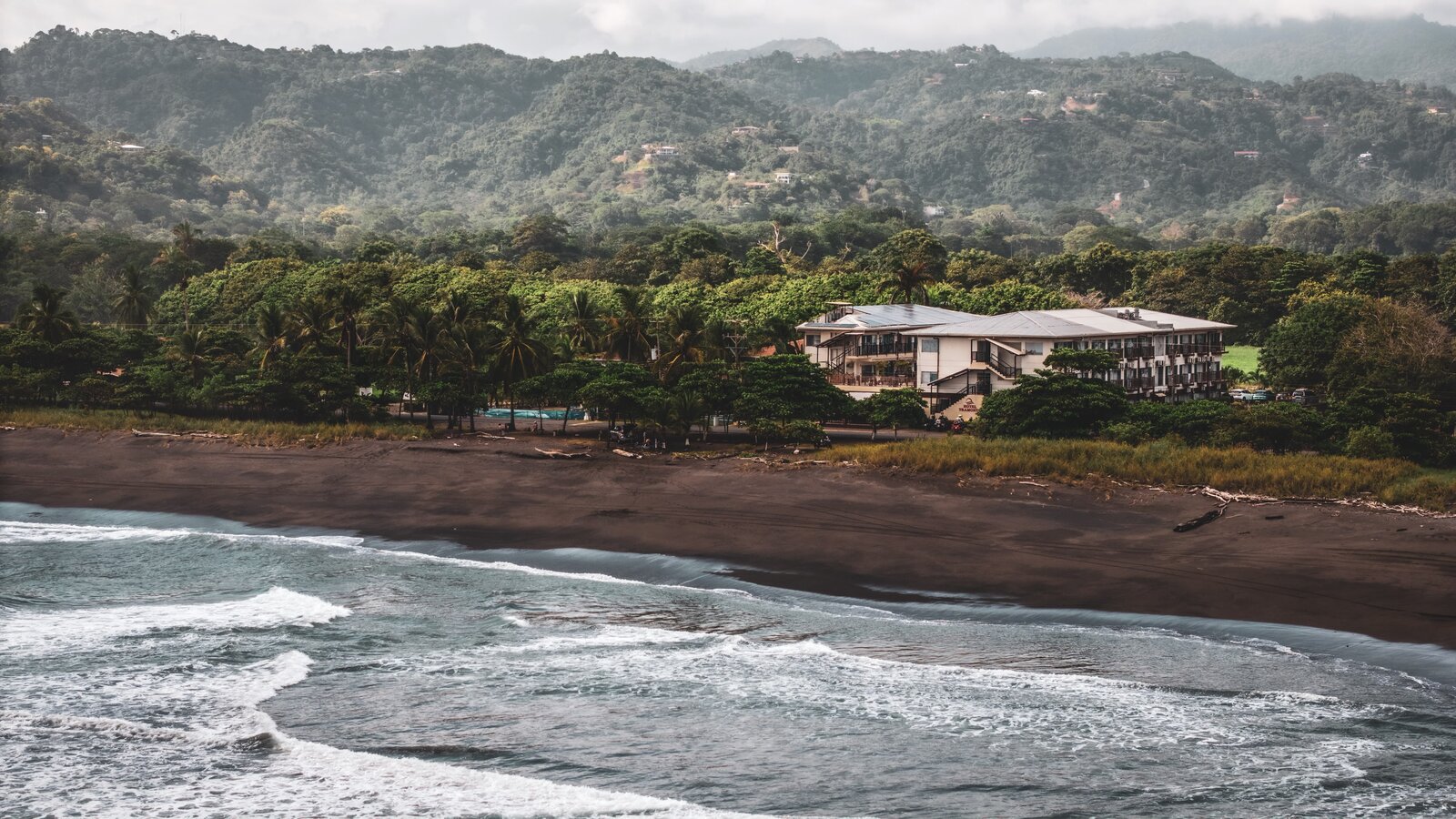 Praia Hermosa, no litoral do Pacífico da Costa Rica, com ondas fortes e morros verdes.