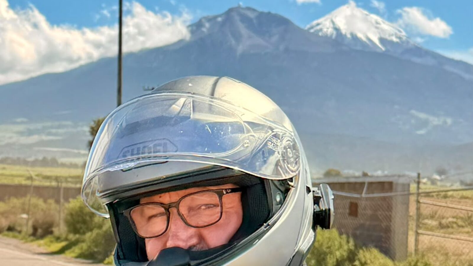 Piloto com o Pico de Orizaba nevado ao fundo, na autopista mexicana