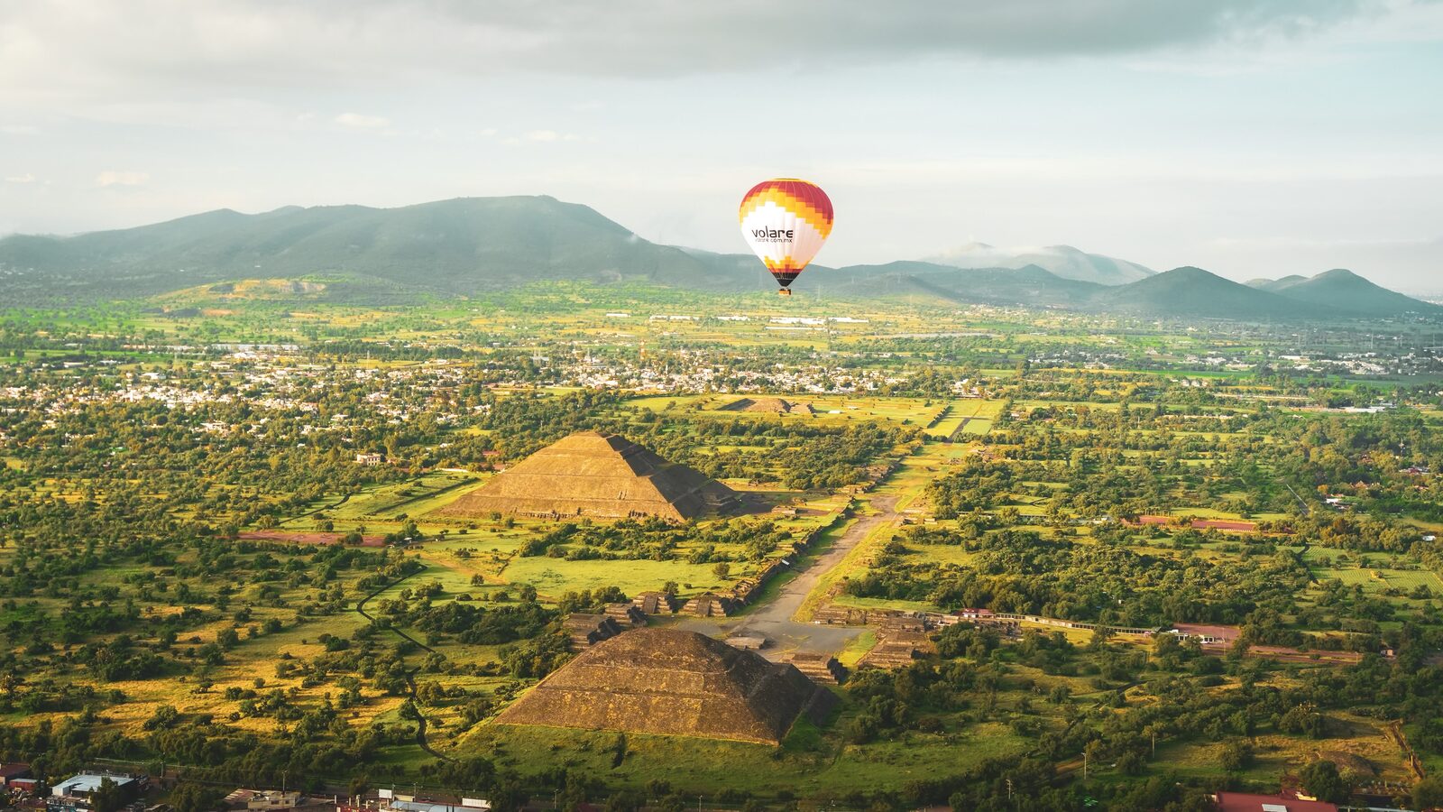 Pirâmides do Sol e da Lua de Teotihuacán vistas do alto, com um balão sobrevoando