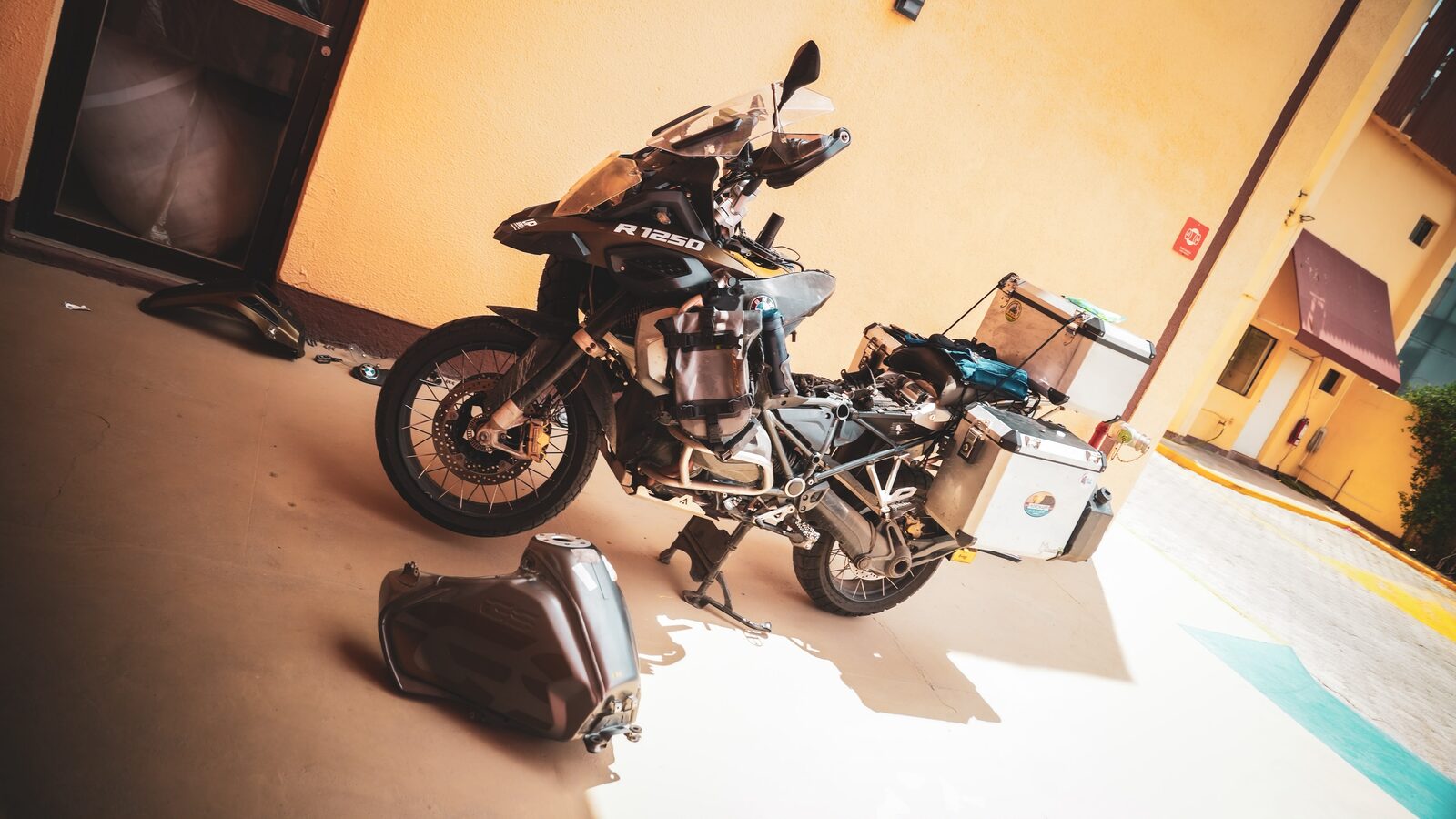 BMW R 1250 GS desmontada no estacionamento do hotel, com o tanque no chão