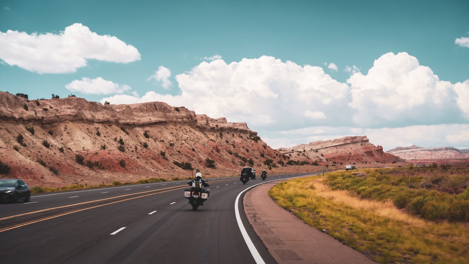 Grupo pilotando por uma estrada entre paredões de rocha vermelha no deserto do Novo México