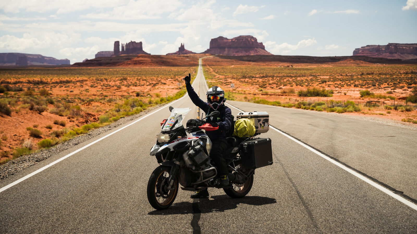 Piloto em movimento numa BMW GS com as formações rochosas do Monument Valley ao fundo