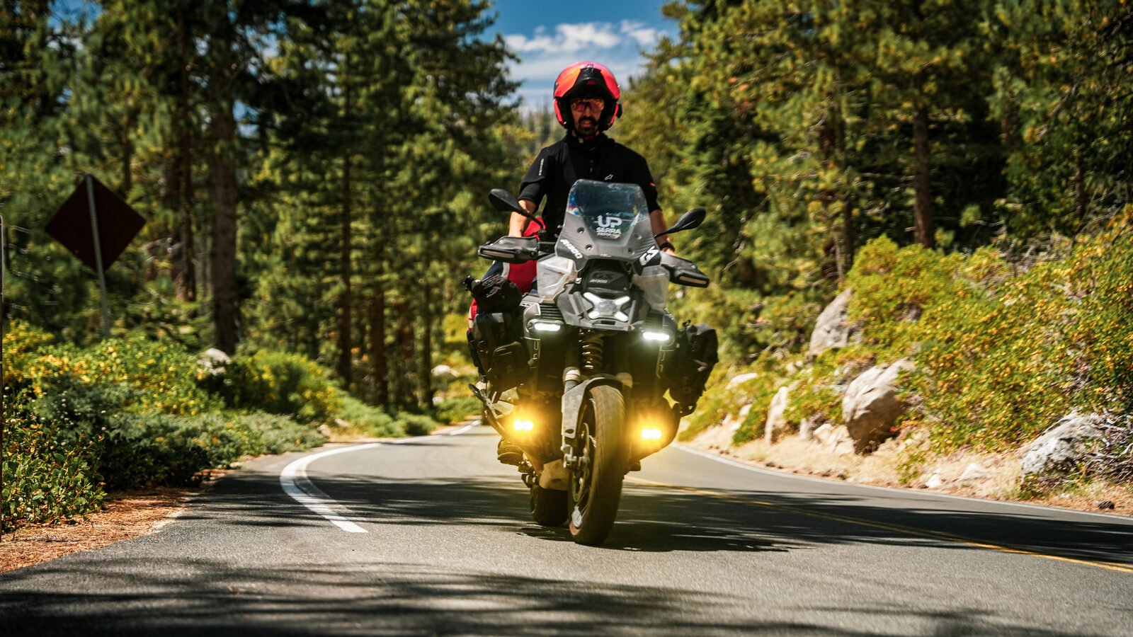 Piloto numa BMW GS pela estrada da floresta de Yosemite
