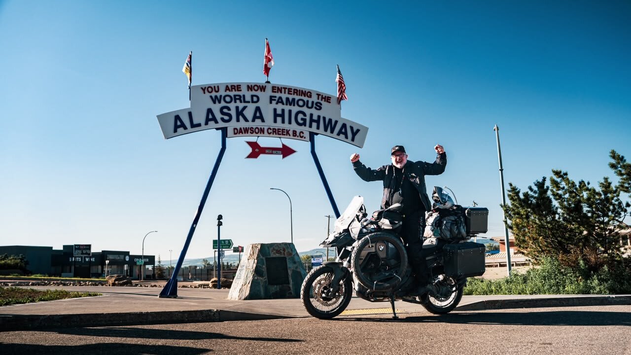 Piloto de braços erguidos na arca do Mile 0 da Alaska Highway em Dawson Creek